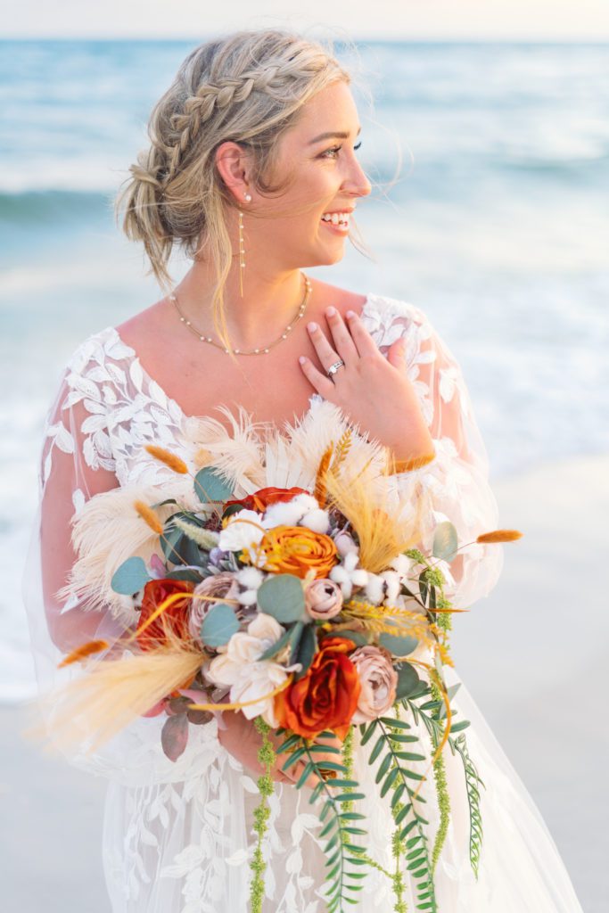 boho chic beach bride with bouquet and ring shot in the sunset on the beach