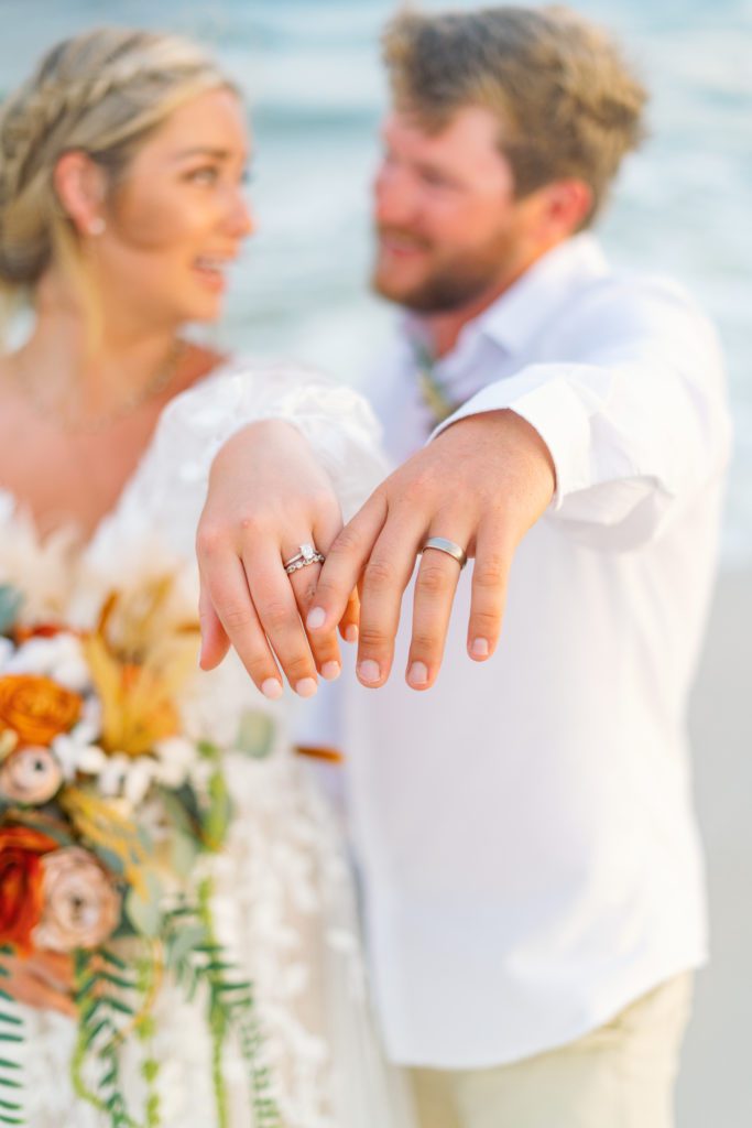 bride and groom show off rings for picture after intimate beach wedding